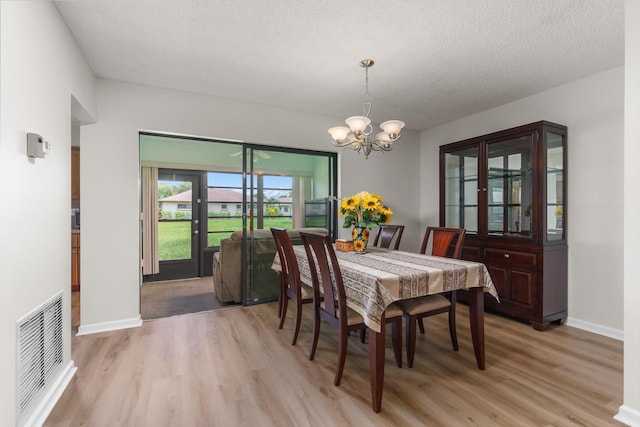 dining area with an inviting chandelier, light hardwood / wood-style flooring, and a textured ceiling