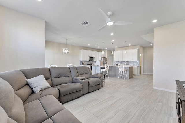 living room with ceiling fan with notable chandelier