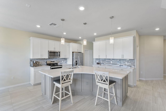 kitchen featuring stainless steel appliances, a large island with sink, white cabinets, and a kitchen bar