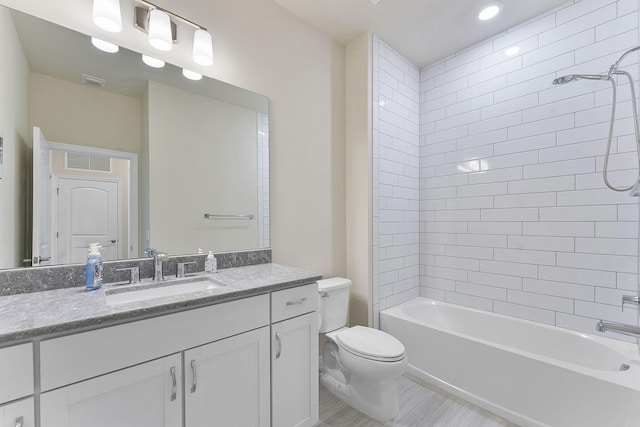 full bathroom featuring vanity, tiled shower / bath, and toilet