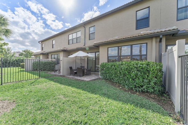 rear view of property featuring a patio area and a lawn