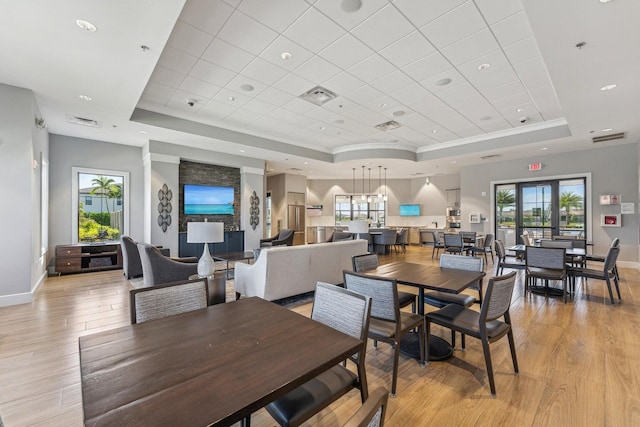 dining room with a wealth of natural light, light wood-type flooring, and a tray ceiling