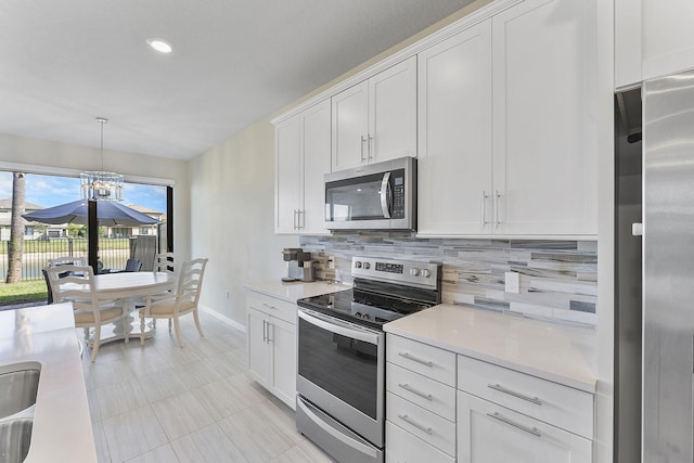 kitchen with hanging light fixtures, decorative backsplash, stainless steel appliances, and white cabinets