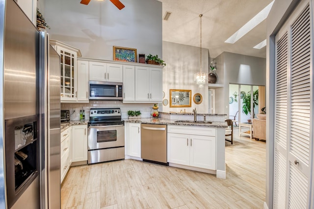 kitchen featuring pendant lighting, sink, white cabinetry, stainless steel appliances, and light stone countertops