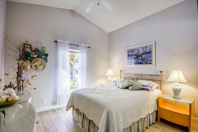 bedroom with ceiling fan, lofted ceiling, light hardwood / wood-style flooring, and a textured ceiling