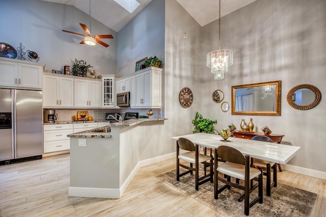 kitchen with stainless steel appliances, white cabinetry, light stone countertops, and hanging light fixtures