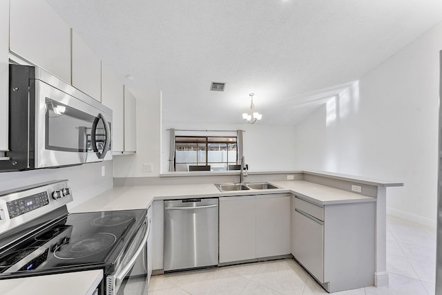 kitchen featuring appliances with stainless steel finishes, pendant lighting, sink, a chandelier, and kitchen peninsula