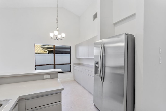 kitchen with high vaulted ceiling, stainless steel fridge, a chandelier, hanging light fixtures, and light tile patterned floors