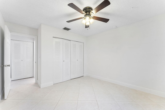 unfurnished bedroom with ceiling fan, light tile patterned floors, a textured ceiling, and a closet