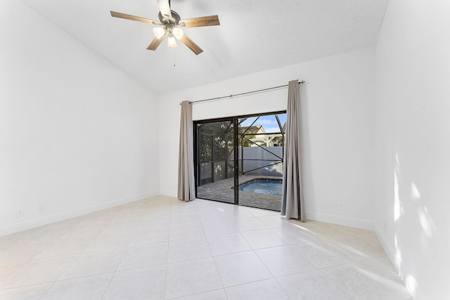 tiled spare room with ceiling fan, vaulted ceiling, and a textured ceiling