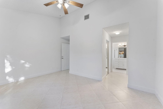 unfurnished room with a towering ceiling, ceiling fan, and light tile patterned flooring