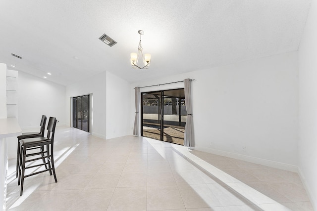 tiled empty room featuring lofted ceiling, a textured ceiling, and an inviting chandelier