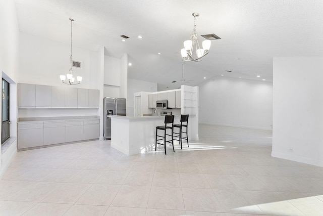 kitchen featuring stainless steel appliances, a large island, a notable chandelier, and decorative light fixtures