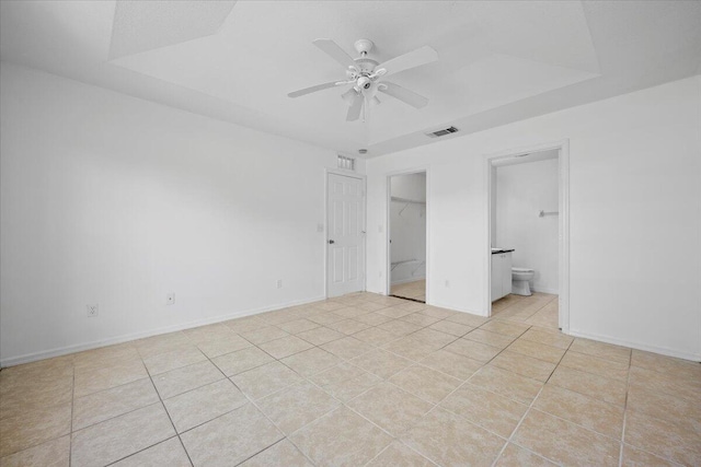 unfurnished bedroom with light tile patterned floors, ensuite bath, a closet, and ceiling fan