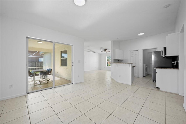 kitchen with light tile patterned floors, ceiling fan, white cabinets, washer / dryer, and kitchen peninsula