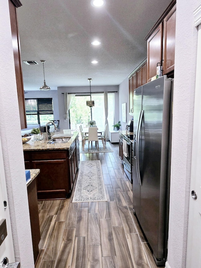 4582 San Fratello Cir, Lake Worth, FL 33467 - kitchen with appliances with stainless steel finishes, a sink, recessed lighting, hanging light fixtures, and light stone countertops
