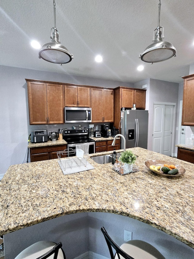 4582 San Fratello Cir, Lake Worth, FL 33467 - kitchen featuring appliances with stainless steel finishes, a breakfast bar, a sink, hanging light fixtures, and brown cabinetry
