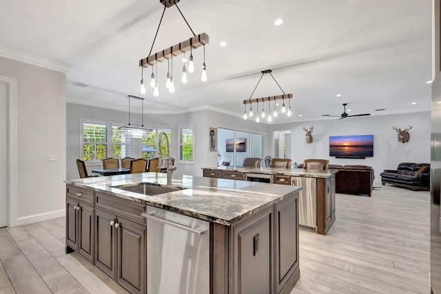 kitchen featuring dishwasher, a kitchen island with sink, hanging light fixtures, light stone countertops, and light hardwood / wood-style floors