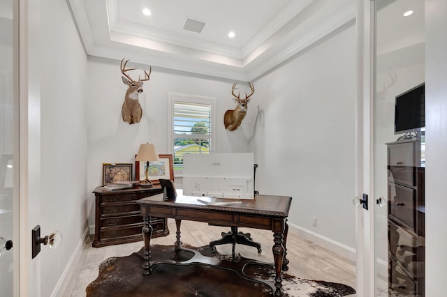 office area with a raised ceiling, ornamental molding, and light wood-type flooring