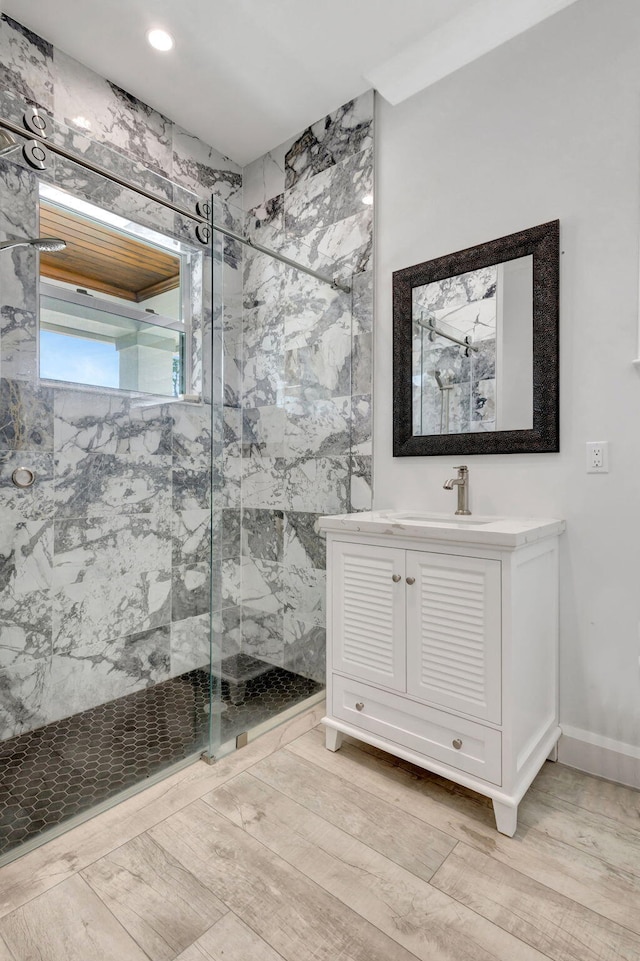 bathroom featuring vanity, wood-type flooring, and a tile shower