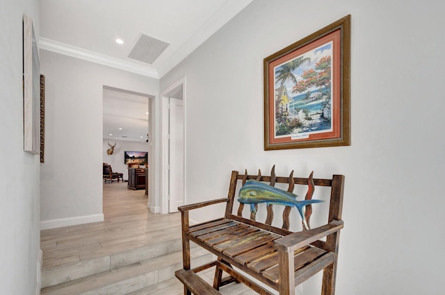 hall with ornamental molding and light hardwood / wood-style floors