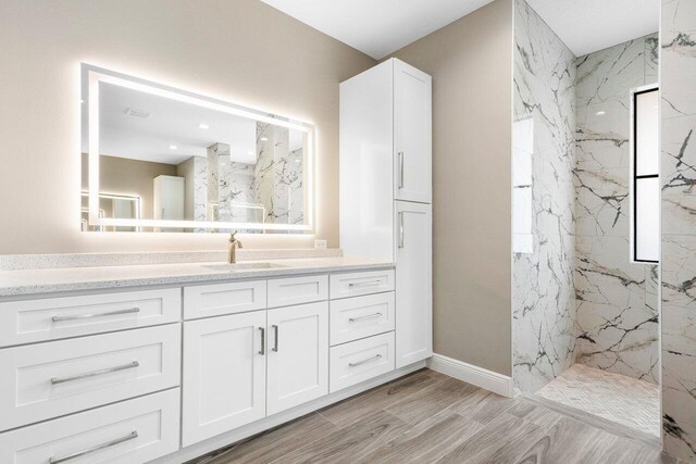 bathroom featuring tiled shower and vanity