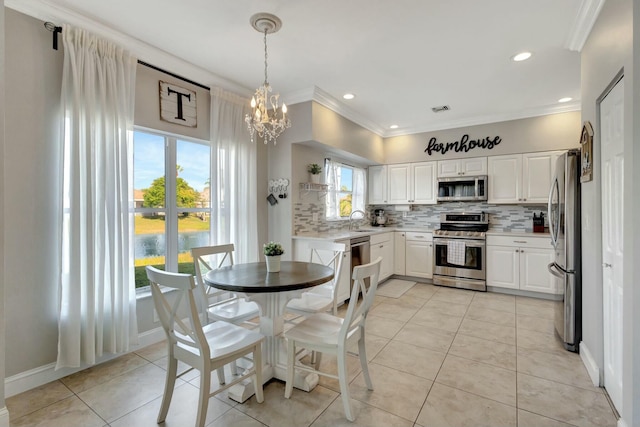 kitchen featuring appliances with stainless steel finishes, decorative light fixtures, white cabinetry, sink, and decorative backsplash