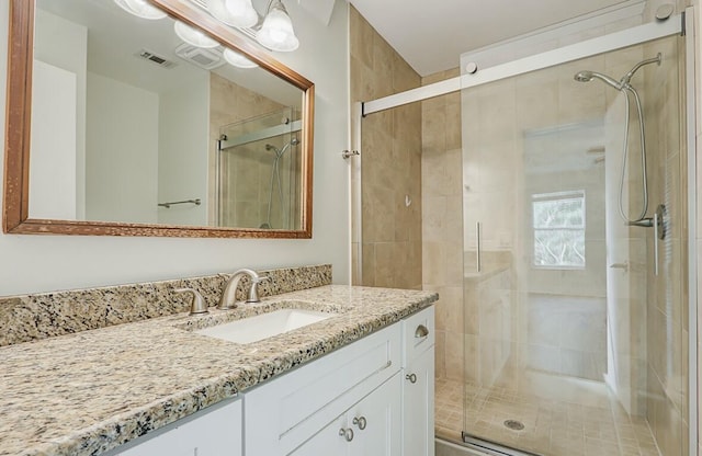 bathroom with a shower with door and vanity