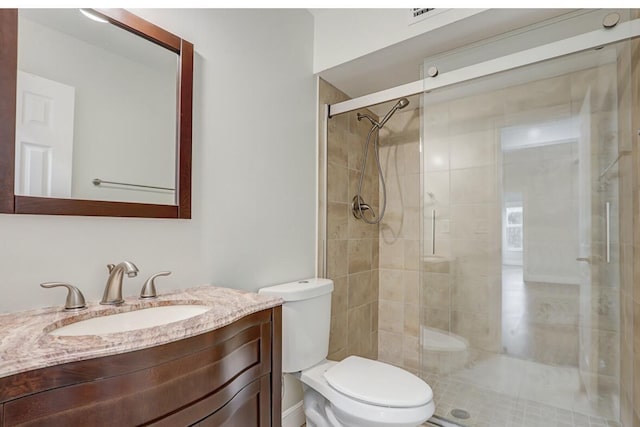 bathroom featuring vanity, a shower with shower door, and toilet