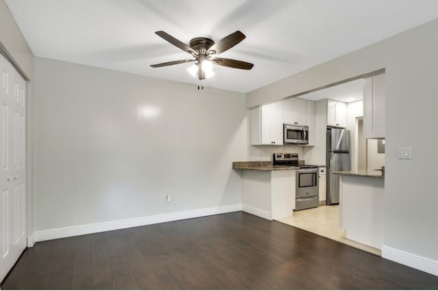 kitchen with light wood-type flooring, stainless steel appliances, baseboards, and white cabinets