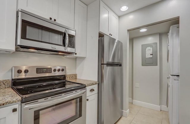 kitchen with stainless steel appliances, light tile patterned flooring, white cabinets, and light stone counters