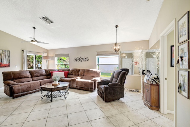 living room featuring vaulted ceiling, ceiling fan with notable chandelier, light tile patterned floors, and a textured ceiling