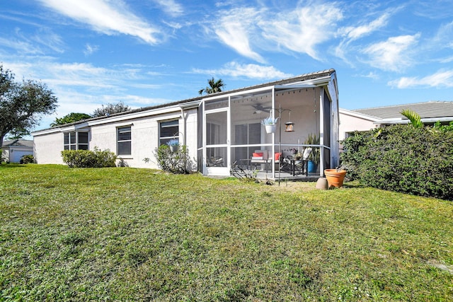 back of property with a sunroom, a yard, and ceiling fan