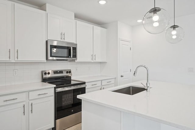 kitchen with a sink, decorative backsplash, light countertops, stainless steel appliances, and white cabinetry