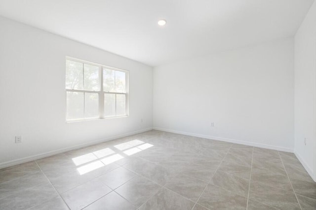 empty room featuring light tile patterned floors and baseboards