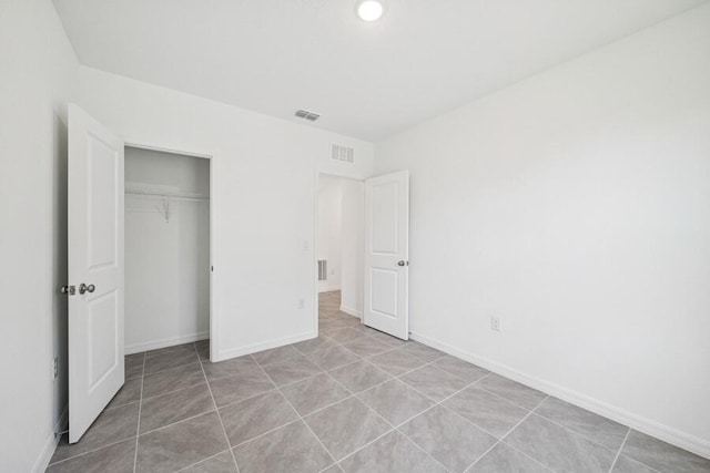 unfurnished bedroom with light tile patterned floors, visible vents, baseboards, and a closet