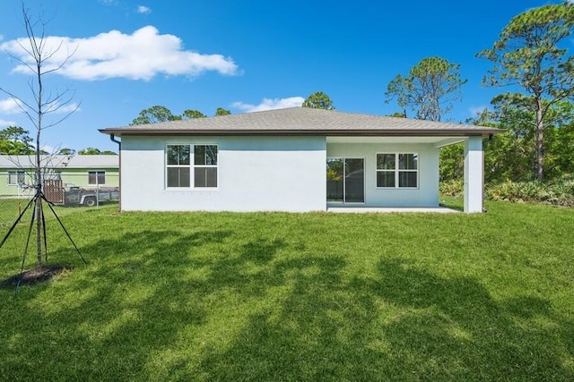 back of property featuring stucco siding, a lawn, and fence