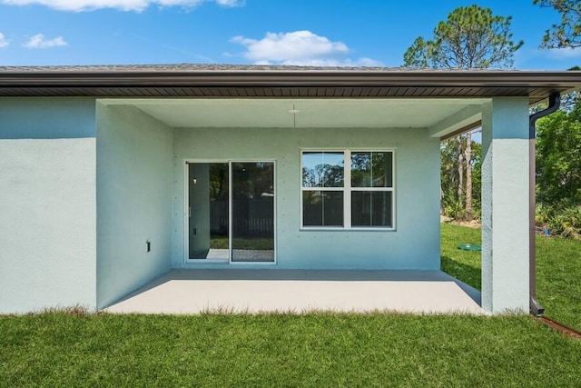 rear view of house with a lawn and stucco siding