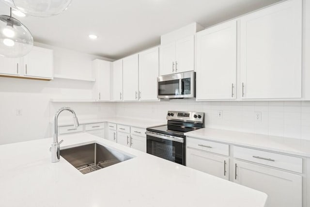 kitchen featuring a sink, stainless steel appliances, light countertops, white cabinetry, and tasteful backsplash