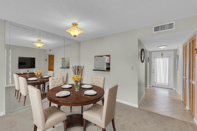 carpeted dining room with a textured ceiling