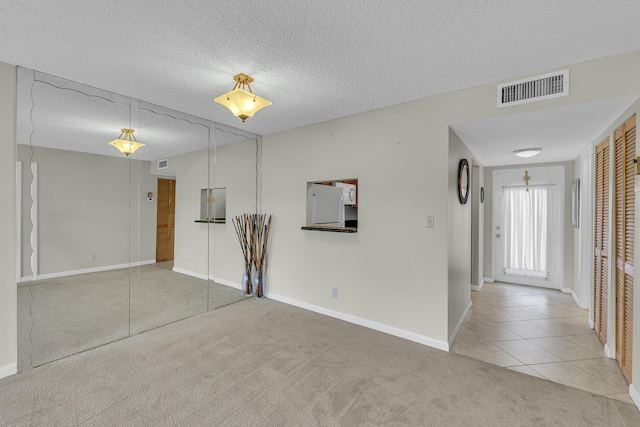 empty room featuring light colored carpet and a textured ceiling