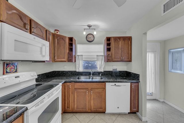 kitchen featuring white appliances, dark stone countertops, sink, and light tile patterned floors