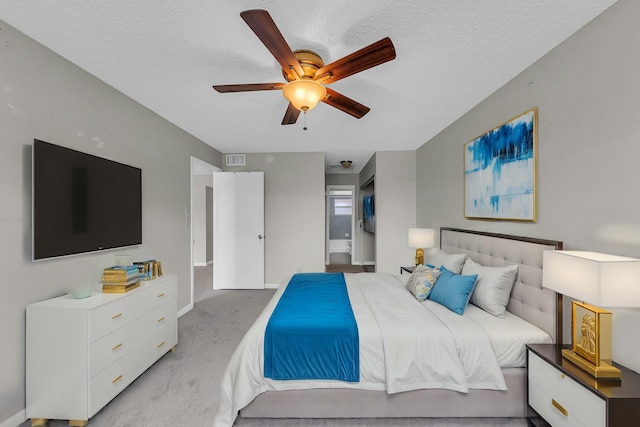 carpeted bedroom with ceiling fan and a textured ceiling