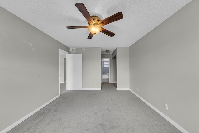 empty room with ceiling fan, light carpet, and a textured ceiling