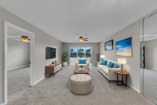 living room featuring ceiling fan, light carpet, and a textured ceiling