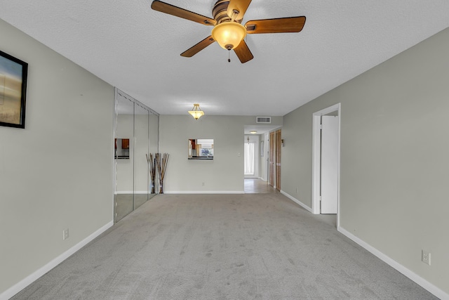 unfurnished living room with ceiling fan, light colored carpet, and a textured ceiling