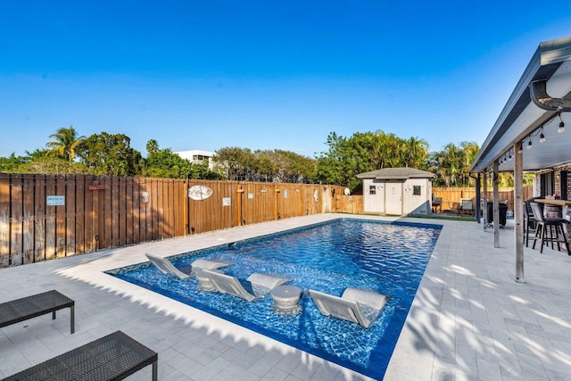 view of swimming pool featuring a patio and a storage shed