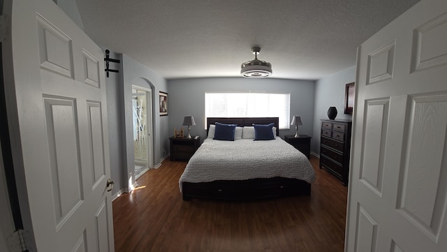 bedroom with dark wood-type flooring, a barn door, and a textured ceiling