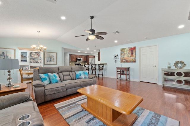 living room featuring dark wood-type flooring, lofted ceiling, and ceiling fan with notable chandelier