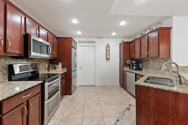 kitchen with sink, light tile patterned floors, stainless steel appliances, and light stone countertops